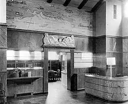 A black and white photo of the interior of a library, showing a bas-relief and a mural