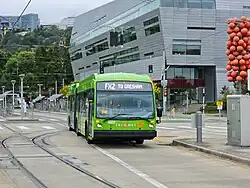 A long green bus travels on exclusive bus lanes