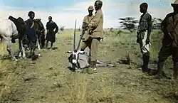 An antelope on the ground and riders around it.