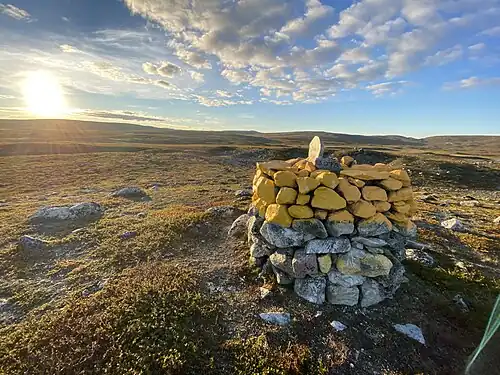 Finland–Norway border cairn 307a, dated 1925, near Siđusgohpi in Reisa National Park. The border reindeer fence is visible on the left.