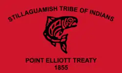 Flag of the Stillaguamish Tribe of Indians. The flag is a red banner with a salmon drawn in the traditional Coast Salish art style. Above the salmon is written "Stillaguamish Tribe of Indians." Below the salmon is written "Point Elliott Treaty 1855"