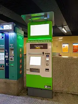 A green an white ticket machine indoors