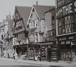 Old photograph of Tudor building with wooden buildings in the protruding upper floors.