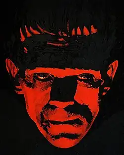 Painting of the face of Frankenstein's monster, illuminated in red and surrounded by darkness