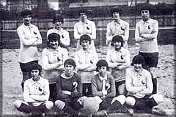 Black and white photo of 12 women sitting and standing in football gear.