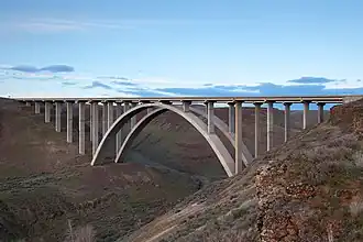 An arch bridge set against a desert-like landscape