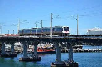A two-car train crossing a metal girder bridge over a river