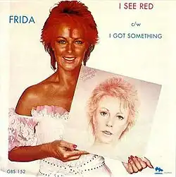 A photo of Lyngstad with red hair and darkly tanned skin, holding a photo of herself with pale skin and blonde hair.