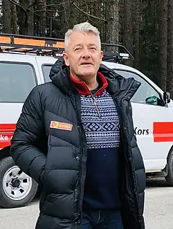 Gjert Ingebrigtsen wearing a winter coat, standing in front of a white van