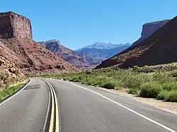 Highway through a sandstone gorge, with the Colorado River (not visible) next to the right side of the road.