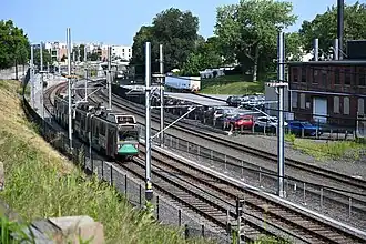 A light rail train on the ramp to a viaduct in an urban area