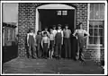 A group of doffers working in Cotton Factory posed by the superintendent of the factory. November 1910. Photographed by Lewis Hine.
