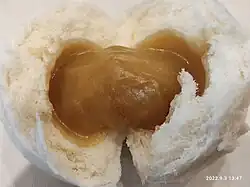 A split-open lotus seed bun, showing the lotus seed paste filling inside.