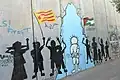 A bilingual Arabic–Catalan graffiti near Bethlehem, featuring the words for 'freedom' alongside the Estelada and the flag of Palestine