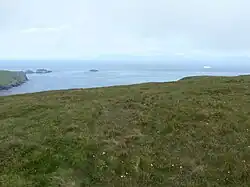 View towards Muckle Flugga and Out Stack from Saxa Vord. Out Stack is the one in the centre (the white shape on right is a ship).