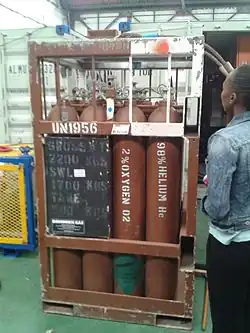 Frame of square tubing supporting a 4 by 4 array of upright 50 litre heliox storage cylinders