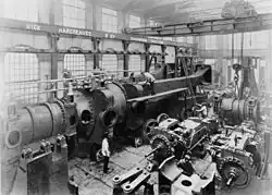 Under assembly c.1890, half of one of the two 10,000 hp engines completed for Deptford Power Station at Hick, Hargreaves and Co.[115][116][117][118] A travelling crane and hoist above.