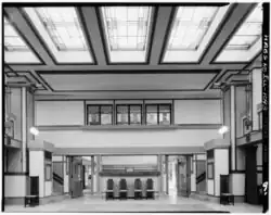 Interior of Unity House, looking north toward the temple. The ceiling has rectangular glass skylights with wood borders. The foyer is visible in the background.