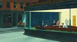 Several people sit at the counter of a brightly lit diner at night