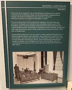 A photo taken in 2023 of an informational sign displayed in the hallway of the 8th floor (Eisenhower Suite) of the Fitzsimons Building. The sign details the uses of the repurposed Bushnell Auditorium during the President's stay.