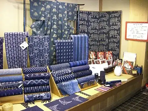 Tanmono, traditional narrow Japanese fabric bolts. This is cotton dyed with indigo before weaving (kasuri) Behind is a yukata (type of kimono) made from this cloth.