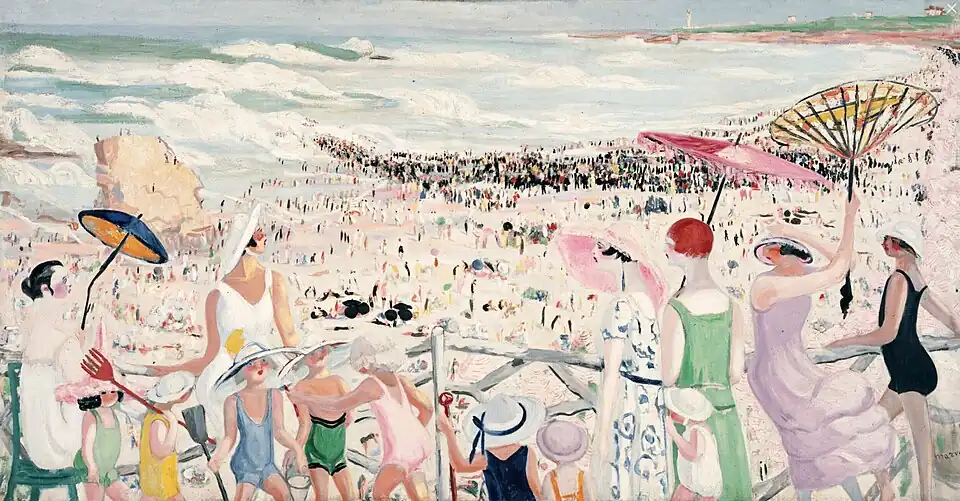 Five women in sundresses, three with parasols, a woman in a bathing suit, and eight children in hats and bathing suits are by a fence overlooking a crowded beach, the sea, and a white lighthouse in the distance.
