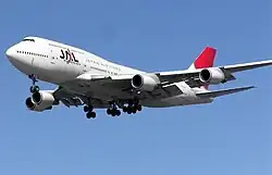 A Boeing 747-400 aircraft in mid-air, with blue sky in the background