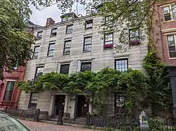 A pair of mirror-image granite row houses with mostly unadorned, flat facades