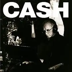 A black-and-white photo of Cash seated in a recording studio with a microphone in front