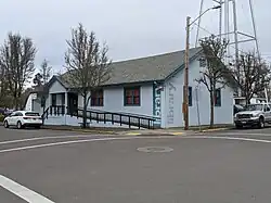 A single-level blue building with a triangular roof and a handicapped ramp. The word "library" pained on the side vertically.