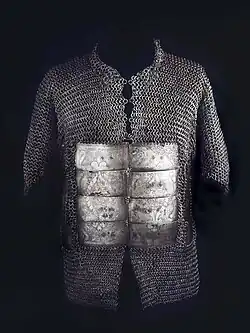 Shirt for a human torso, made of interlinked metal rings, with eight engraved metal plates on the belly area