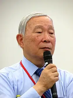 Kakutarō Kitashiro holding a microphone.