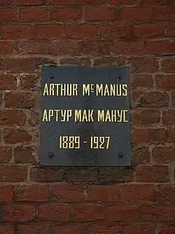 Plaque on a brick wall with inscription: Arthur MacManus/Артур Макманус, 1889–1927