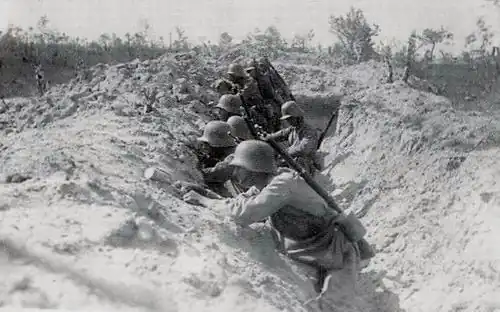 A black and white image of soldiers looking left over the walls of a trench