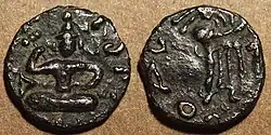 Coin of Kujula Kadphises. Obv Kujula seated cross legged facing, Kharoshti legend: Kuyula Kadaphasa Kushanasa. Rev Zeus on the reverse,[12] Greek legend: ΚΟΖΟΛΑ XOPANOY ZAOOY.