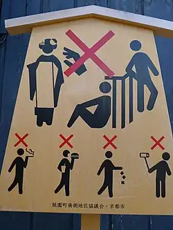 A sign prohibition tourists doing various activities, including touching geisha, leaning on a handrail, smoking, eating, drinking, littering, and using selfie sticks.
