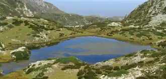 A body of water surrounded by green hills.