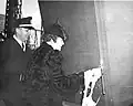 LST-344 launching, 15 December 1942. Mrs. Bonnie Ward, Wife of H.H. Ward, Master Machinist, Inside Machine Shop Master, christens the ship at Norfolk Navy Yard, Portsmouth, Virginia with Lieutenant R. I. Coleman, Aide to the Commandant, also on the platform.