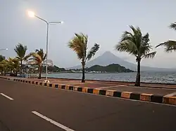 Coconut-tree lined seaside boulevard with view of the sea and Mayon Volcano