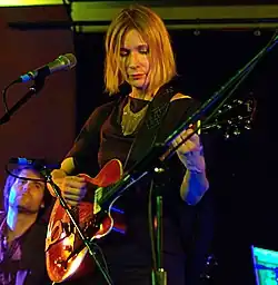 blonde woman playing guitar