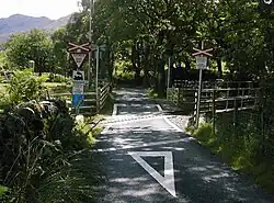 An open crossing on a narrow gauge heritage railway in Beddgelert, Gwynedd, with bilingual warning signage