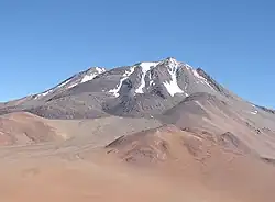 An irregular mountain with elongated snow patches descending its slopes
