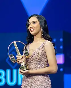 Young female holding a trophy in an awarding ceremony.