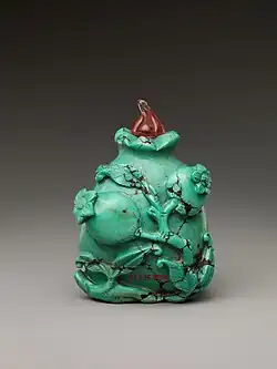 A turquoise bottle with a high-relief rose design wrapping around it