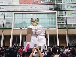 Many people observe the sculpture covered with protective plastic.