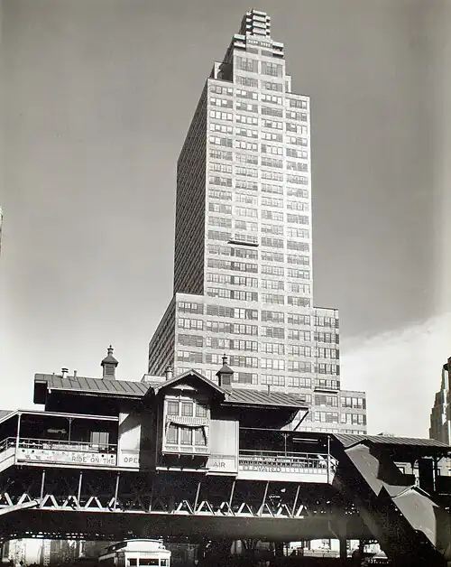 The building as seen from the west after its construction. There is an elevated rail station in front of the building.