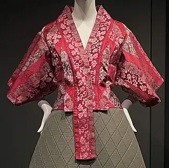 Red short jacket with kimono-inspired embroidery and pattern, on mannequin.
