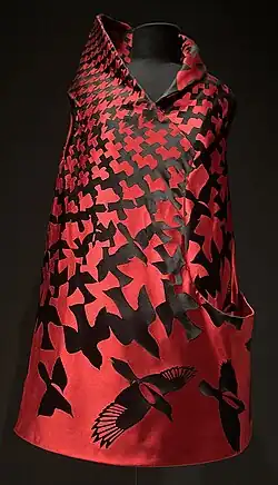 Red sleeveless mini dress with asymmetrical high collar and a pocket on its left side. Dress has a black bird print.