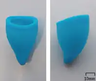 A blue cup with a pointy but unstemmed tip, the rim cut on a slant, the tip curling a bit towards the side where the rim is short, all rounded as if melted