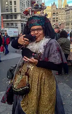Mother Pigeon in Union Square Park. She is holding plush rats and wearing a soft sculpture of a pigeon nest on her head.